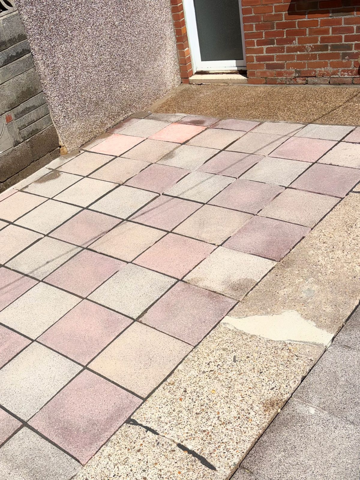 Paving slab patio mid-clean showing stark before and after contrast